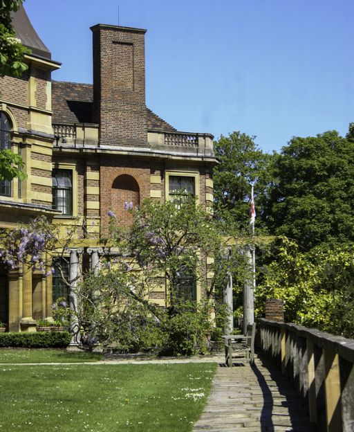 Eltham Palace in Greenwich, showing the historic brick facade with wisteria climbing the walls and gardens in the foreground