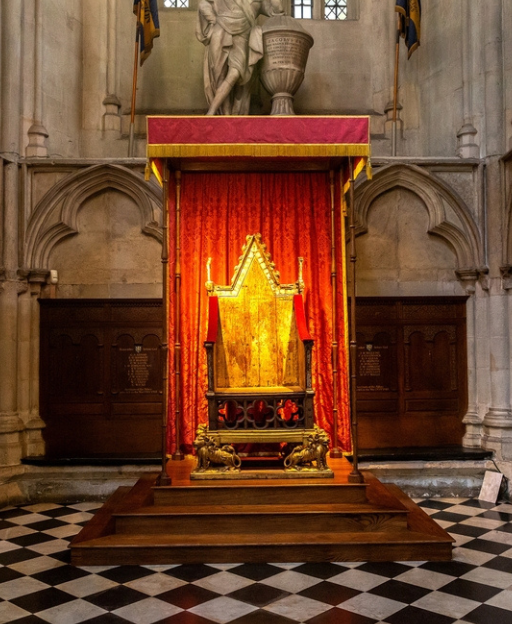 The Coronation Chair in Westminster Abbey, an ancient oak throne with gilded lions and red velvet drapes, used for every British coronation since 1308