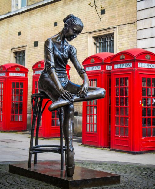 Bronze Young Dancer statue with red telephone boxes outside the Royal Opera House, Covent Garden, London