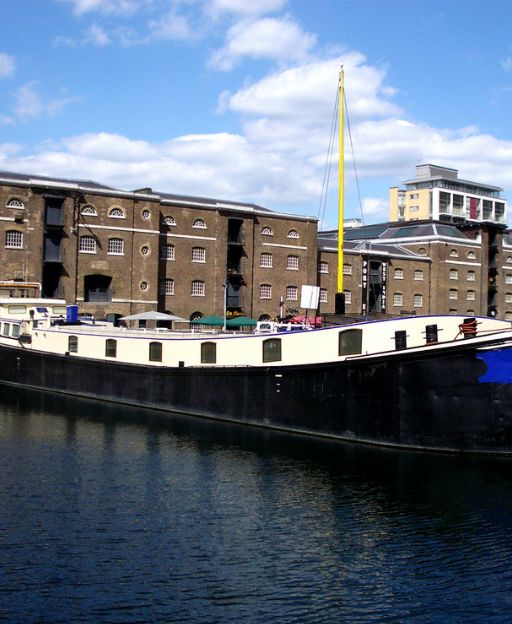 Historic brick warehouses at West India Quay, East London, with a barge moored in the foreground
