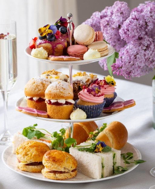 A three-tiered afternoon tea stand with scones, finger sandwiches and pastries in London