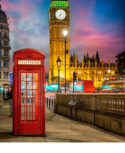 Red telephone box in front of Big Ben at night, London — a classic London scene for first-time American visitors