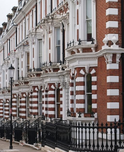 Ornate red and white Victorian townhouses with iron railings on a London street
