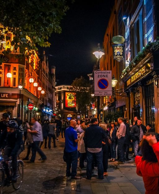 Busy Soho street at night with restaurant lights and crowds of people