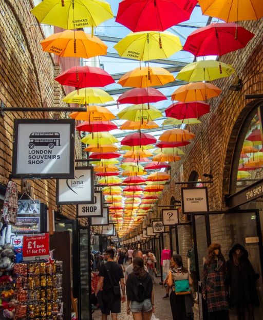 Colourful hanging umbrellas over the cobblestone alley at Camden Market's Stables Market in London