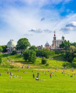 Greenwich Park on a sunny summer day with the Royal Observatory in the background and people relaxing on the grass
