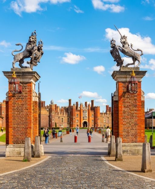 The ornate Tudor gatehouse entrance to Hampton Court Palace, flanked by heraldic beasts atop red brick pillars