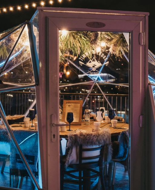 A cosy heated dining pod on London's Southbank, glowing with warm lights on a winter evening
