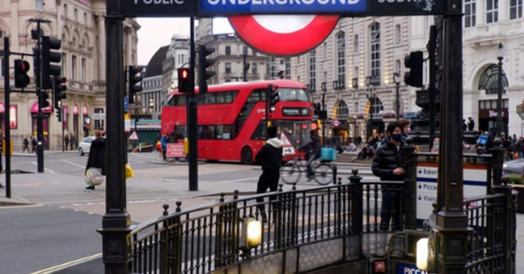 Piccadilly Circus Underground Station entrance with iconic red London Underground sign and red double-decker bus