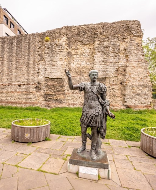 Statue of Roman Emperor Trajan standing before the ancient London Wall in the City of London