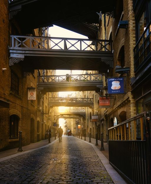 Shad Thames cobbled street with Victorian iron walkways spanning between brick warehouses at golden sunset, Bermondsey London