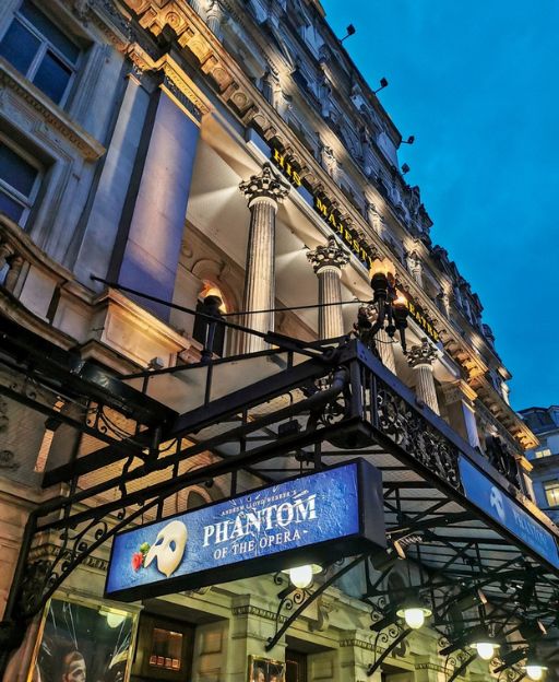 His Majesty's Theatre in London's West End at night, showing the Phantom of the Opera marquee