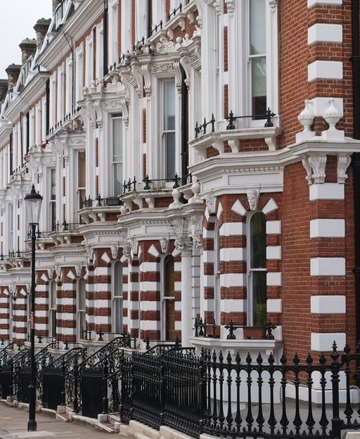 Victorian terraced townhouses in London with red brick, white ornamental details and iron railings