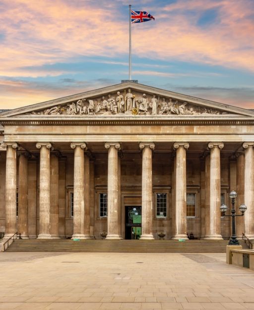 The neoclassical entrance of the British Museum in London, with ionic columns and the Union Jack flag flying above