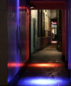 Atmospheric neon-lit alleyway in Soho London at night, showing the vibrant backstreet character of the neighbourhood
