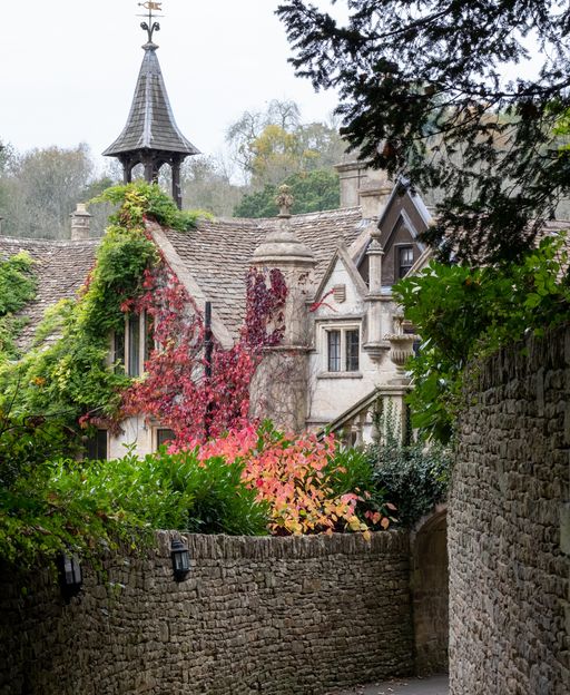 Stone buildings with red autumn climbing plants at Castle Combe village in the Cotswolds, England