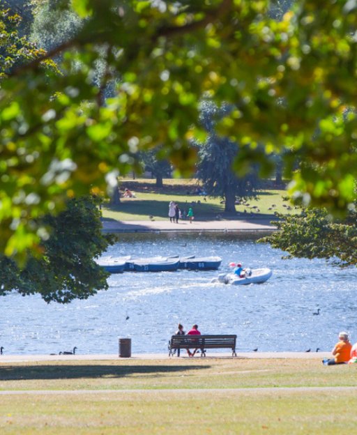 People relaxing by the Serpentine lake in Hyde Park on a warm summer day in London