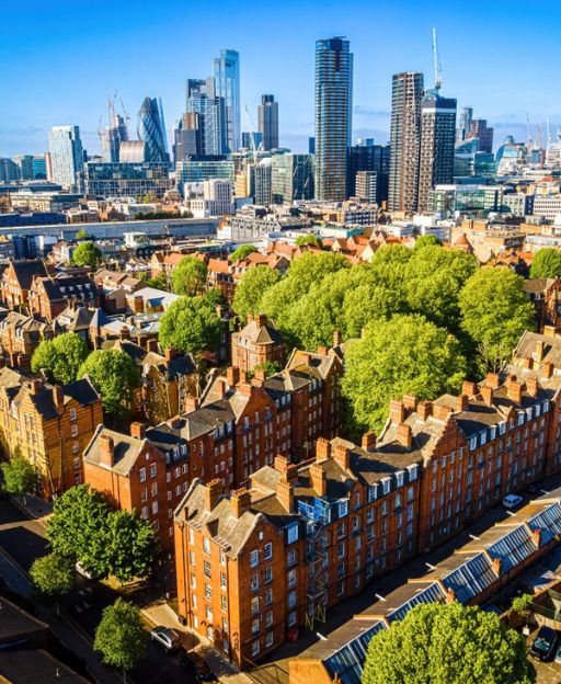 Aerial view of Shoreditch showing Victorian red-brick warehouses in the foreground with the glass towers of the City of London rising behind