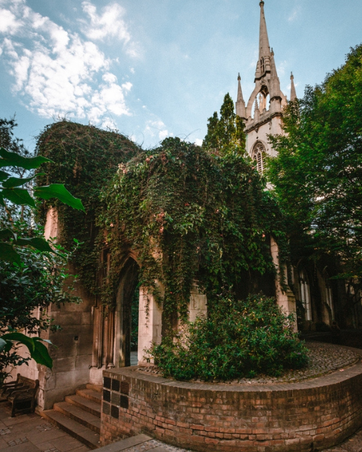Historic London church ruins with ivy-covered walls and a church spire, typical of the area's Huguenot heritage