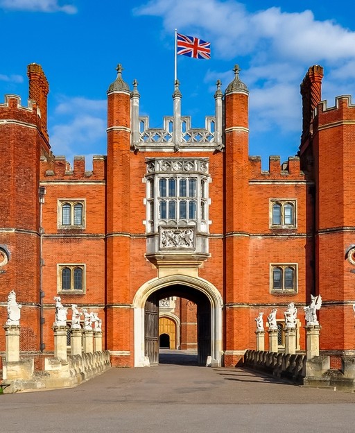 The Tudor gatehouse entrance to Hampton Court Palace with Union Jack flag flying above the red brick towers