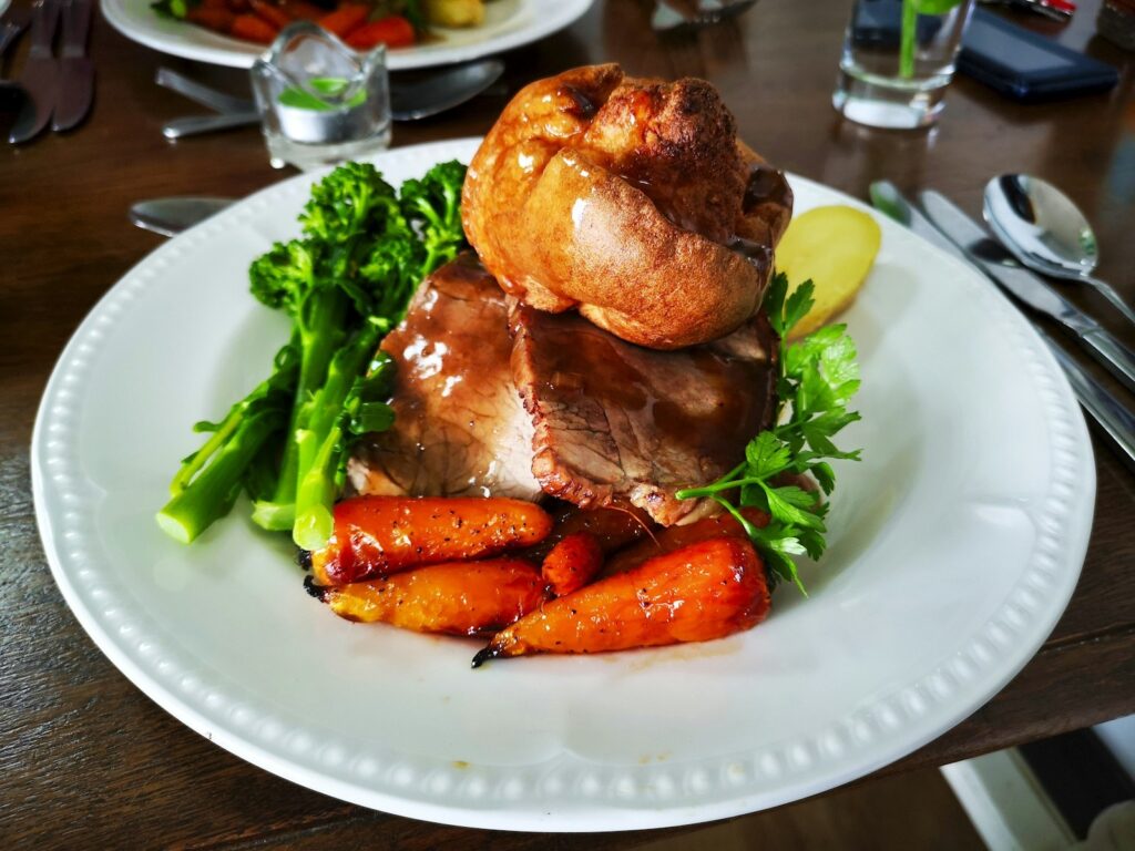 A roast beef dinner with Yorkshire pudding, carrots and greens