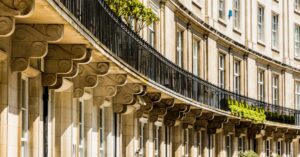 Curved cream stucco terrace of Wilton Crescent in Belgravia, London, with black iron railings