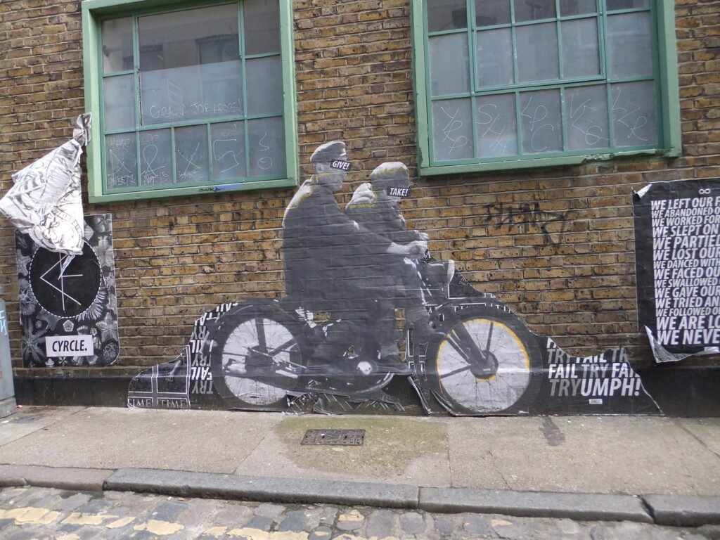 Paste-up artwork of two figures on a motorcycle off Brick Lane