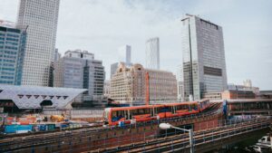 Red train on a viaduct among Canary Wharf towers