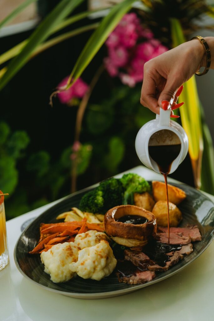 Gravy poured over a roast dinner with Yorkshire pudding and vegetables