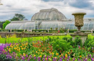 Glass Palm House behind spring flower beds at Kew Gardens, London