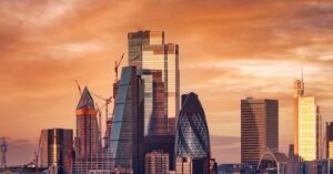 The City of London skyline at sunrise, with the Gherkin and new towers glowing in orange light