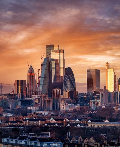 The City of London skyline at sunrise, with the Gherkin and new towers glowing in orange light