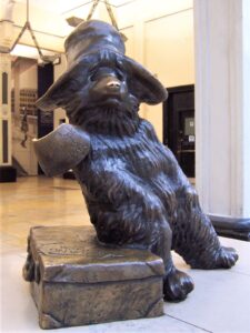 Bronze statue of Paddington Bear in his hat, sitting on his suitcase at Paddington Station, London