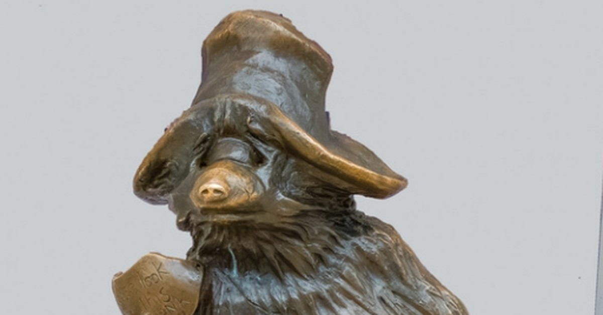 Bronze Paddington Bear statue in his hat and luggage label at Paddington Station, London