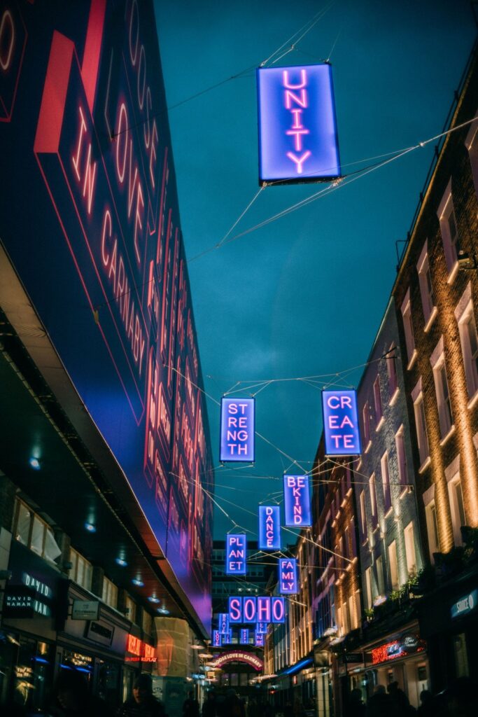 Neon signs hanging over a Soho street at night