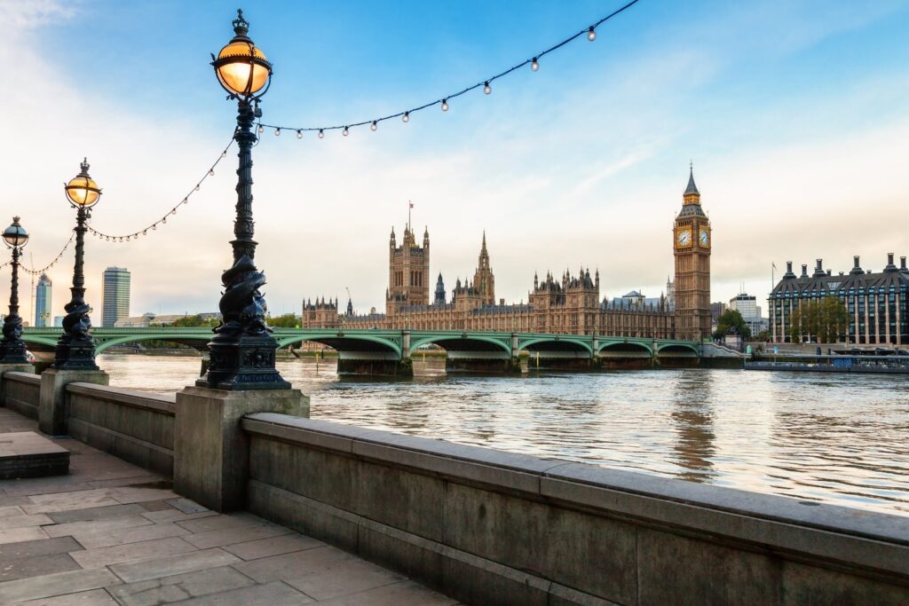 The riverside walk on the South Bank, with dolphin lamp posts and the Palace of Westminster across the Thames