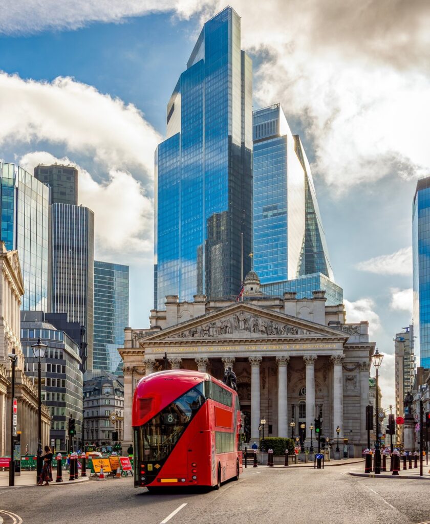 The Royal Exchange and the towers of the City of London, with a red bus passing