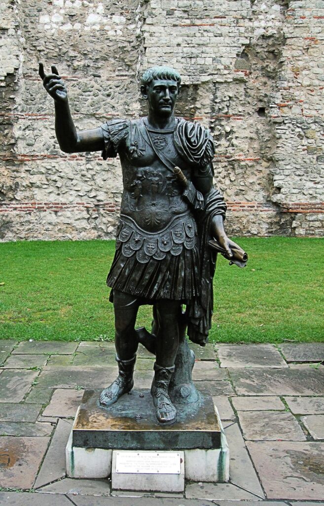 Bronze statue of the Roman Emperor Trajan in front of a surviving stretch of the Roman London Wall at Tower Hill