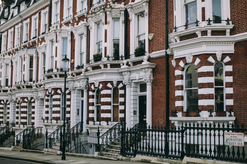 Row of Victorian red-brick townhouses with white stucco details and black iron railings in London