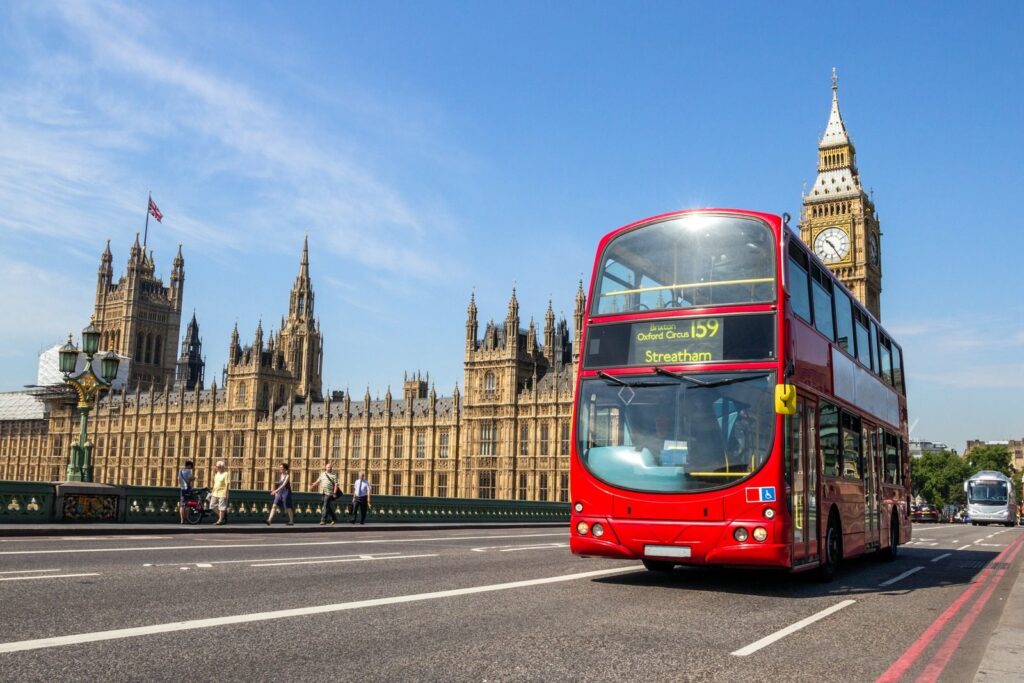 A red bus on Westminster Bridge with the Houses of Parliament behind